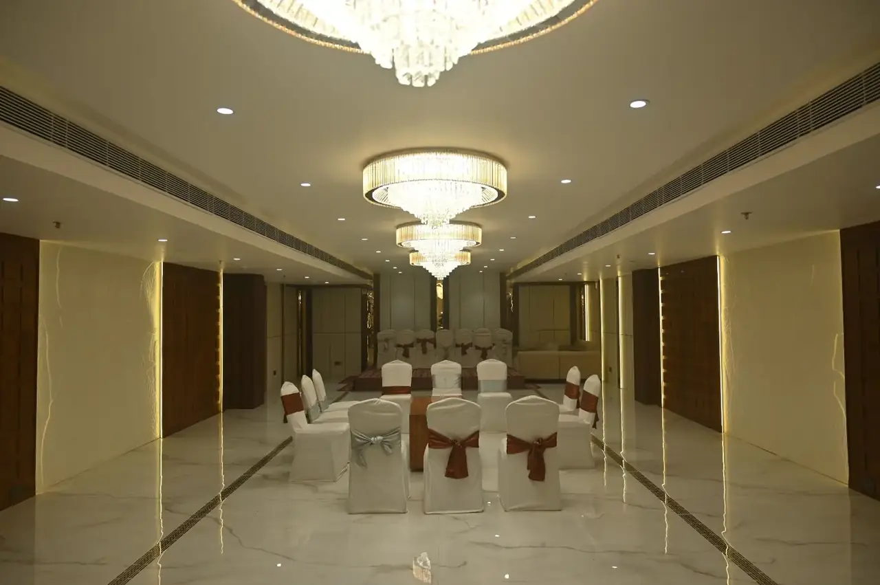 Baithak at Basera Hotel with a decorated stage and seating under round crystal chandeliers