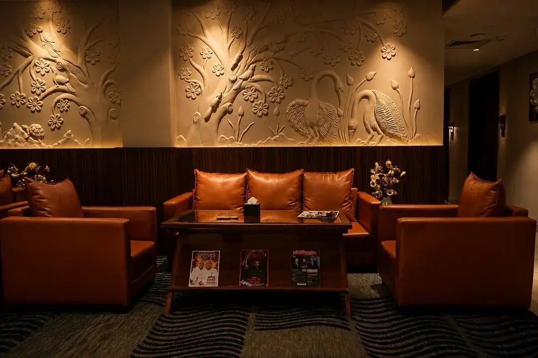 The Basera lounge — tan leather sofas beneath a carved peacock relief wall