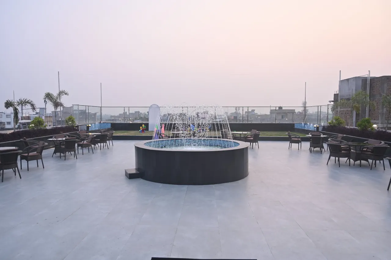 Vatika — open-air rooftop with a fountain and seating, at sunset